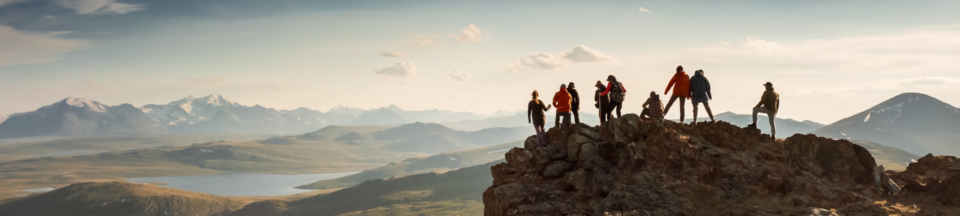 A team of hikers celebrating their achievement atop a mountain surrounded by stunning natural scenery A team of hikers celebrating their achievement atop a mountain surrounded by stunning natural scenery