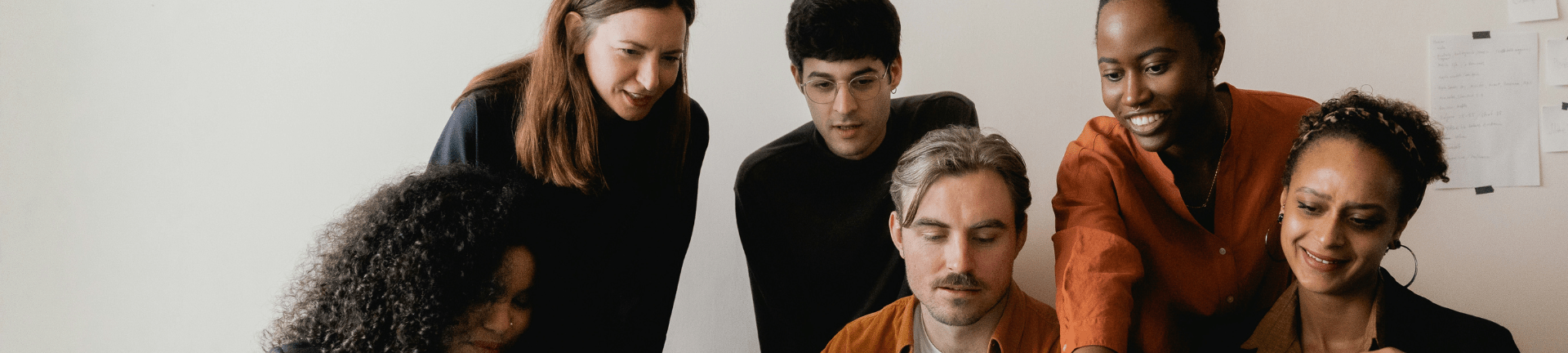 A team of people stands around a table, focused on MSP direct sourcing workforce solutions and collaborative efforts.