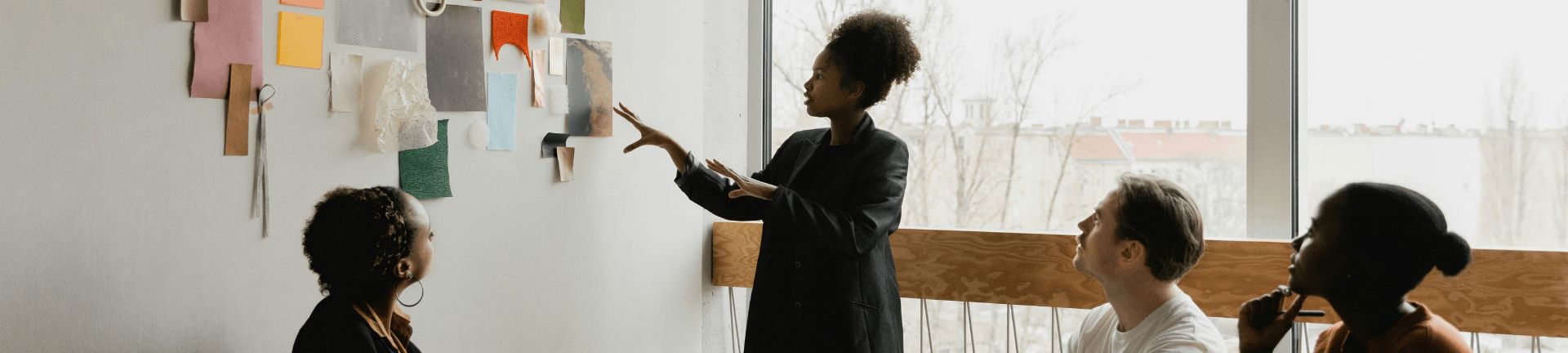 People seated at a table, actively discussing, as one points to a wall, emphasizing a talent advisory session.