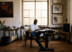 A man is sitting at a cozy workspace in his home office.